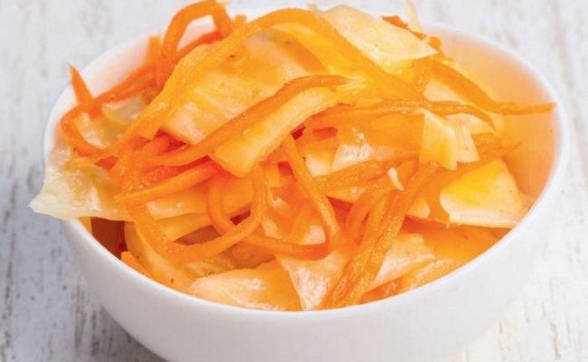 Нарезанная острая капуста с маринованной морковью под железными крышками